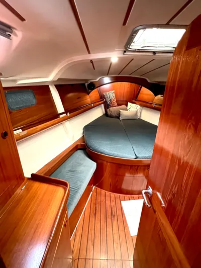 Alpha Carina Yacht Photos Pics Cozy cabin interior of 1993 Beneteau Oceanis 440 sailboat with wooden finishes and cushioned seating.