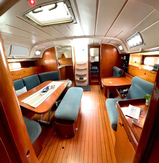 Alpha Carina Yacht Photos Pics Interior of 1993 Beneteau Oceanis 440 sailboat with wood finish and blue seating.