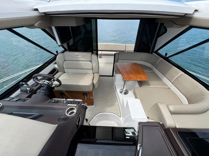 Lake Break Yacht Photos Pics 2016 Regal 42 Sport Coupe interior with helm, seating, and table, overlooking the water.