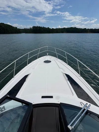 Lake Break Yacht Photos Pics 2016 Regal 42 Sport Coupe cruising on a serene lake under a partly cloudy sky.