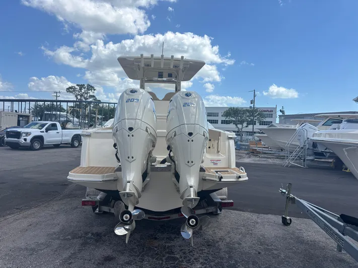  Yacht Photos Pics 2025 Scout 277 LXF boat with dual outboard engines, parked outdoors under a blue sky.