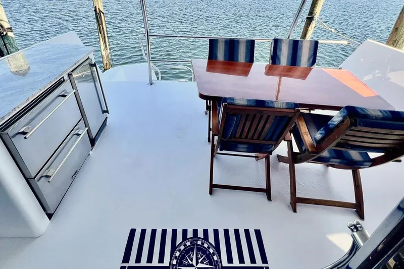 Kristin Lee Yacht Photos Pics Outdoor dining area on 2001 Hatteras 75 Cockpit Motor Yacht with striped chairs and table.