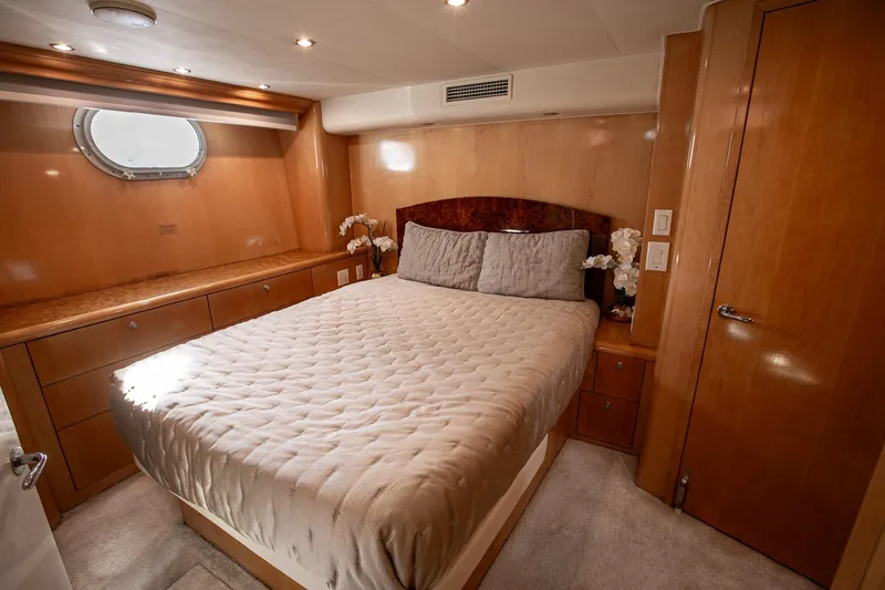 Kristin Lee Yacht Photos Pics Luxurious bedroom interior of 2001 Hatteras 75 Cockpit Motor Yacht with elegant wood finishes.