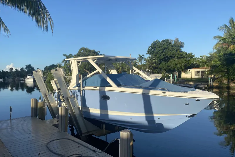  Yacht Photos Pics 2022 Chaparral 280 OSX boat docked on a serene waterfront with lush greenery.