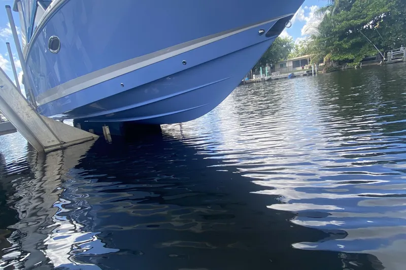  Yacht Photos Pics Blue 2022 Chaparral 280 OSX boat on lift over calm water.