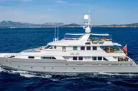 Luxurious 2002 CMN Custom yacht cruising on blue ocean with scenic coastline.