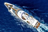Aerial view of a luxurious 2002 CMN Custom yacht cruising through deep blue ocean waters.
