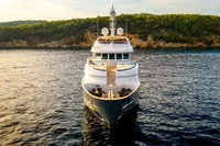 Luxurious 2002 CMN Custom yacht on serene water with lush green coastline.