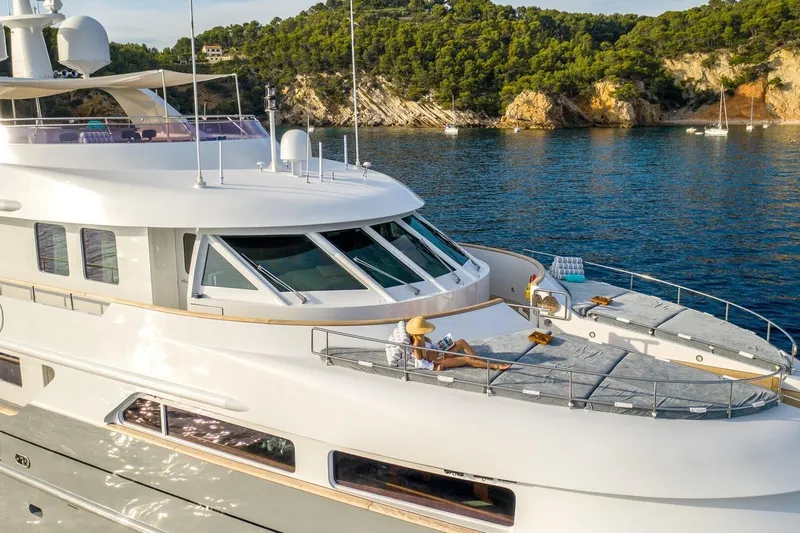  Yacht Photos Pics Luxurious 2002 CMN Custom yacht with sunbathing area, anchored near scenic coastline.