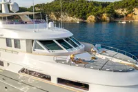 Luxurious 2002 CMN Custom yacht with sunbathing area, anchored near scenic coastline.