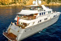 Luxurious 2002 CMN Custom yacht cruising in clear blue waters near rocky coastline.
