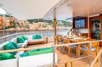 Luxurious yacht deck with dining area, scenic coastal view, CMN Custom 2002 model.