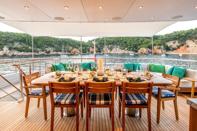  Yacht Photos Pics Luxurious yacht dining setup with ocean view, featuring elegant tableware and comfortable seating.