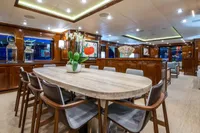Luxurious yacht interior with elegant dining area, modern decor, and wooden finishes, CMN Custom 2002.