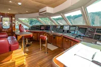 Luxurious yacht cockpit with red leather seats, advanced navigation systems, and panoramic windows. CMN Custom 2002.
