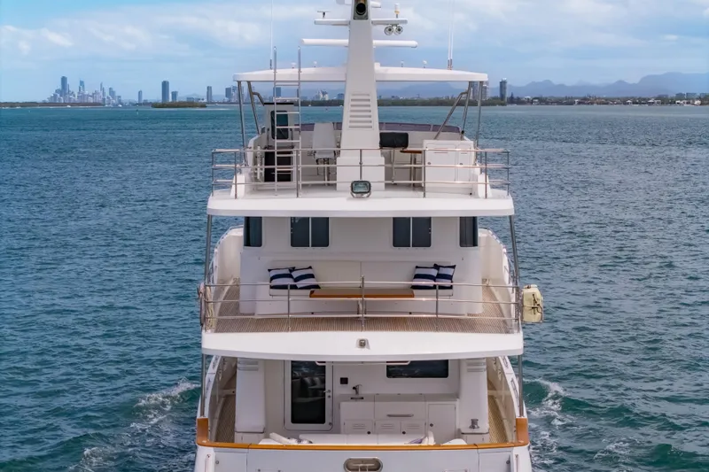  Yacht Photos Pics Luxurious 2013 Nordhavn 68 yacht cruising on open water with city skyline backdrop.