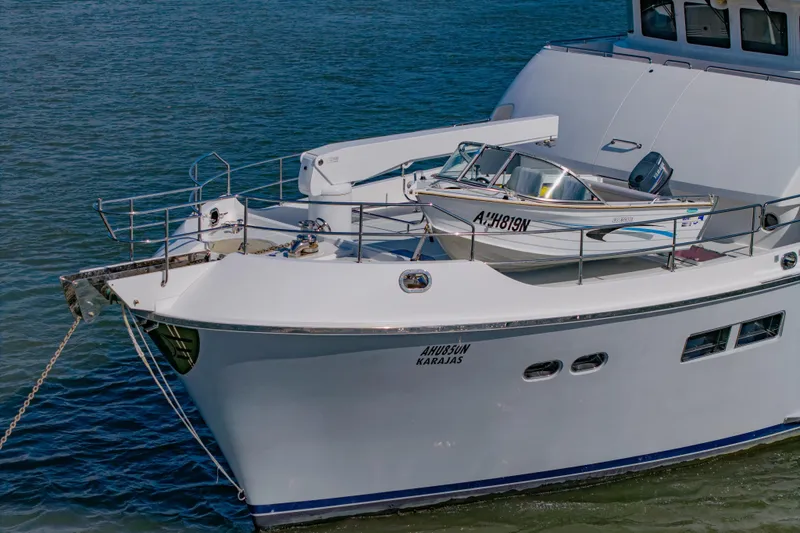  Yacht Photos Pics 2013 Nordhavn 68 yacht with a small boat on deck, anchored in calm waters.