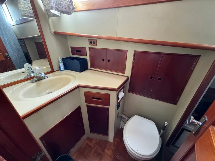 Carolina Breeze Yacht Photos Pics 1989 Grand Banks 42 Motor Yacht bathroom with sink, toilet, and wooden cabinetry.