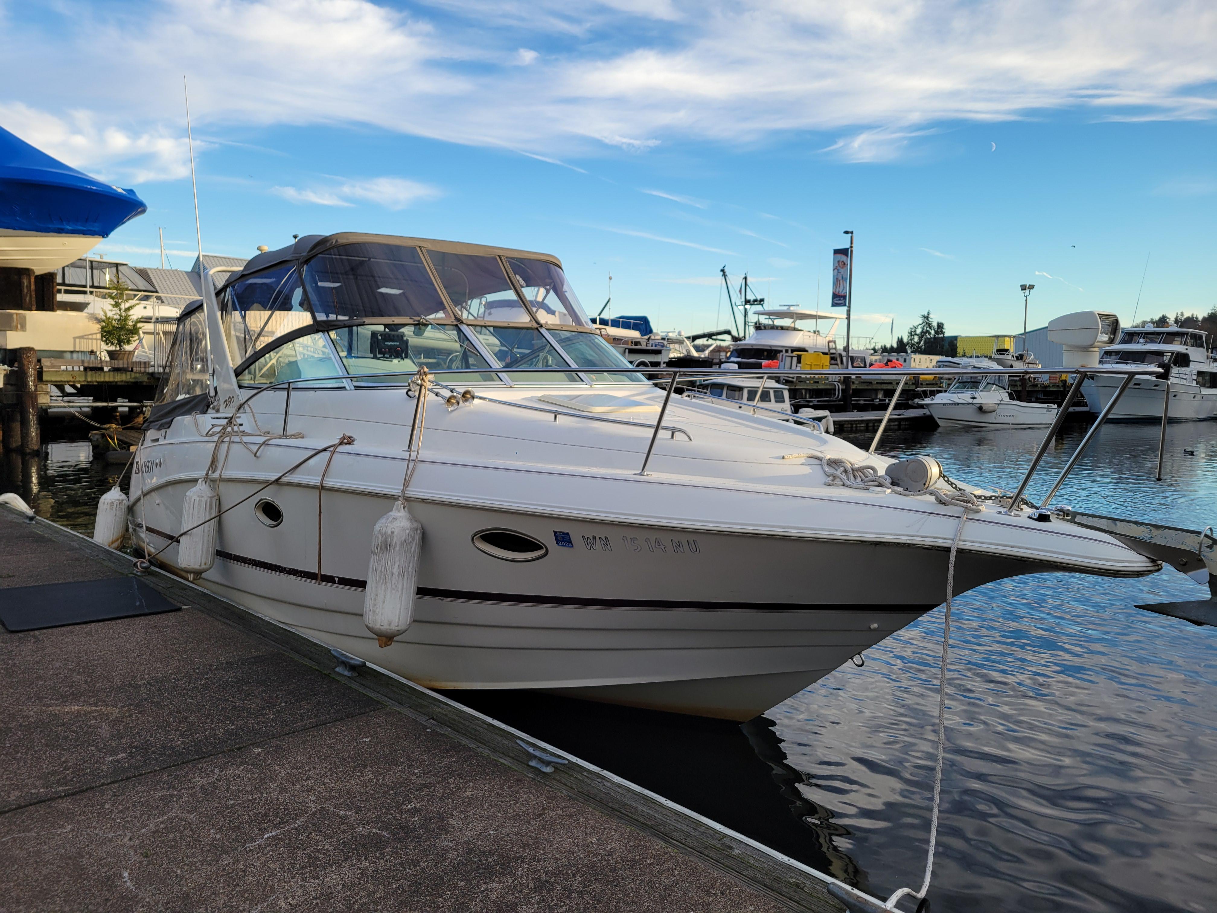 1997 Larson 290 Cabrio boat docked at marina under blue sky.