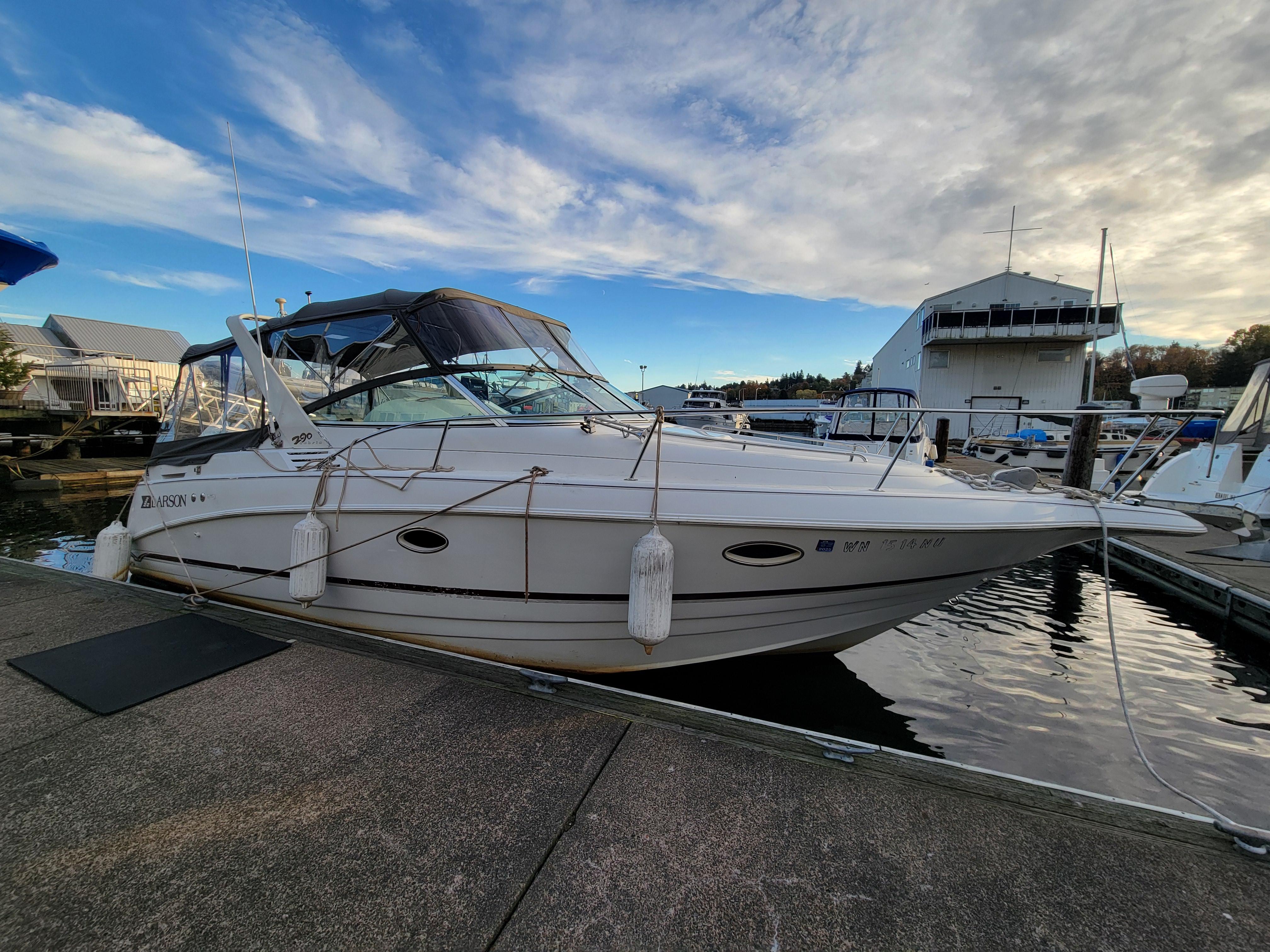 1997 Larson 290 Cabrio boat docked at marina under blue sky.