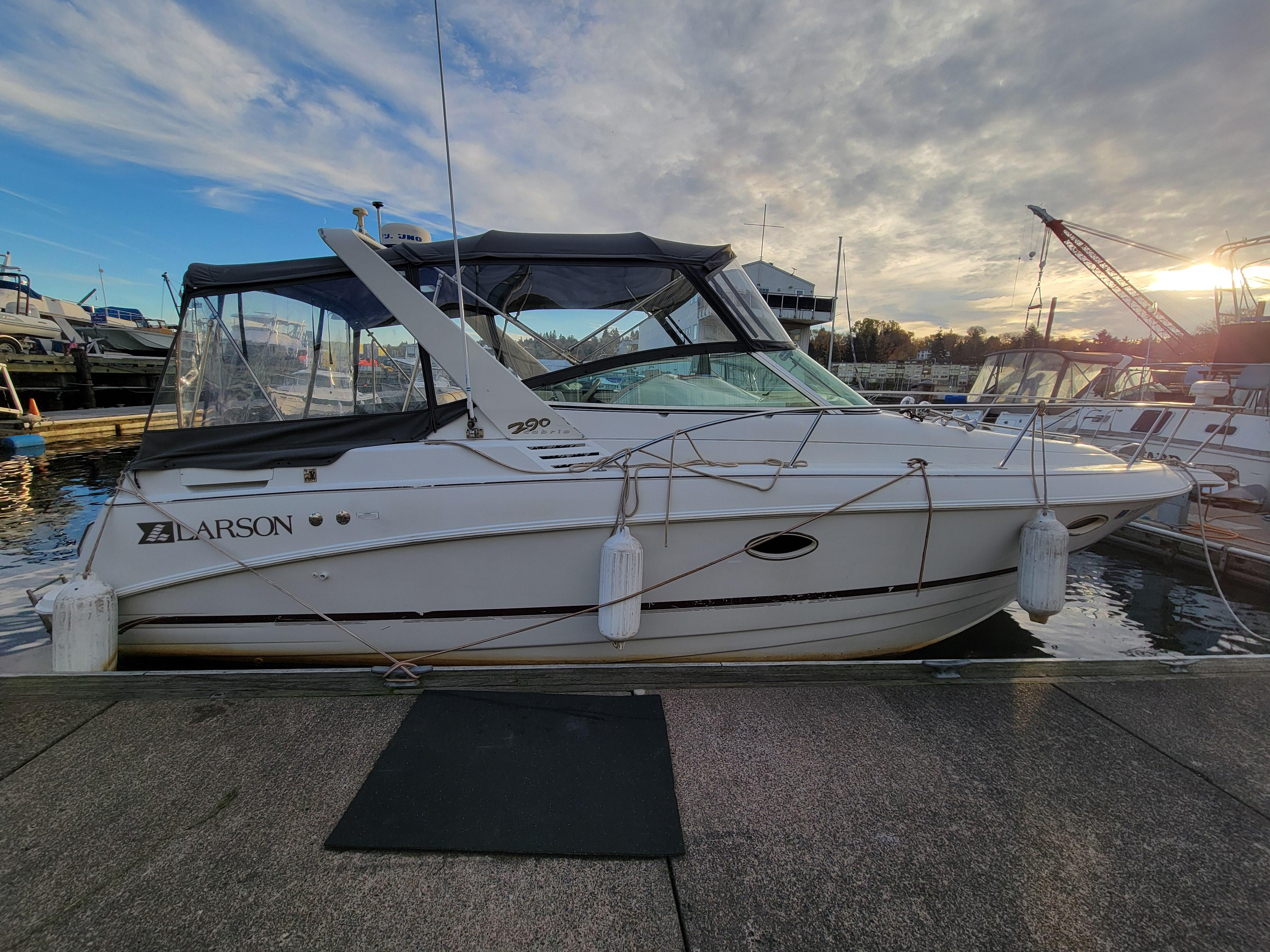 1997 Larson 290 Cabrio boat docked at marina under cloudy sky.
