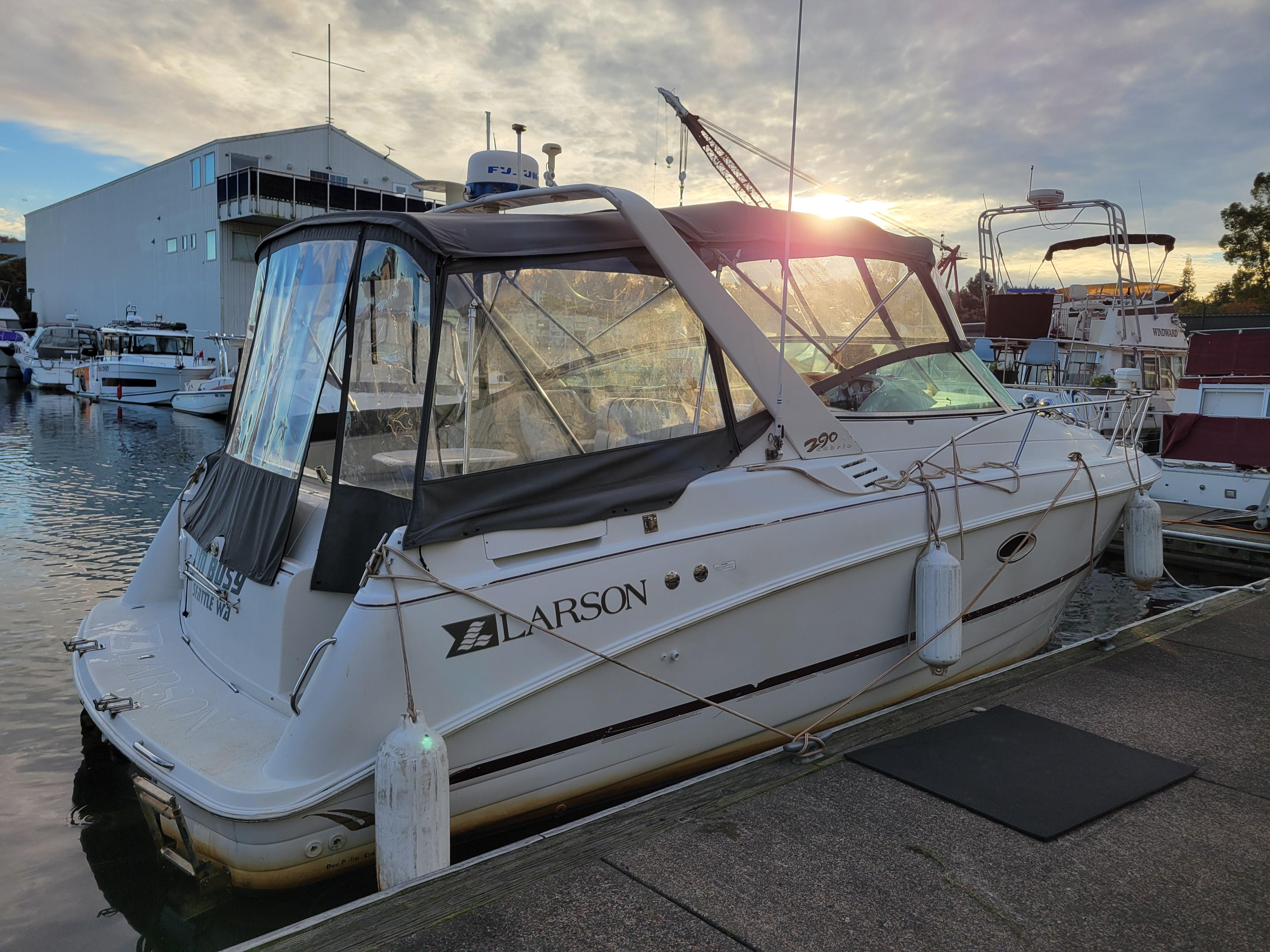 1997 Larson 290 Cabrio boat docked at marina during sunset.