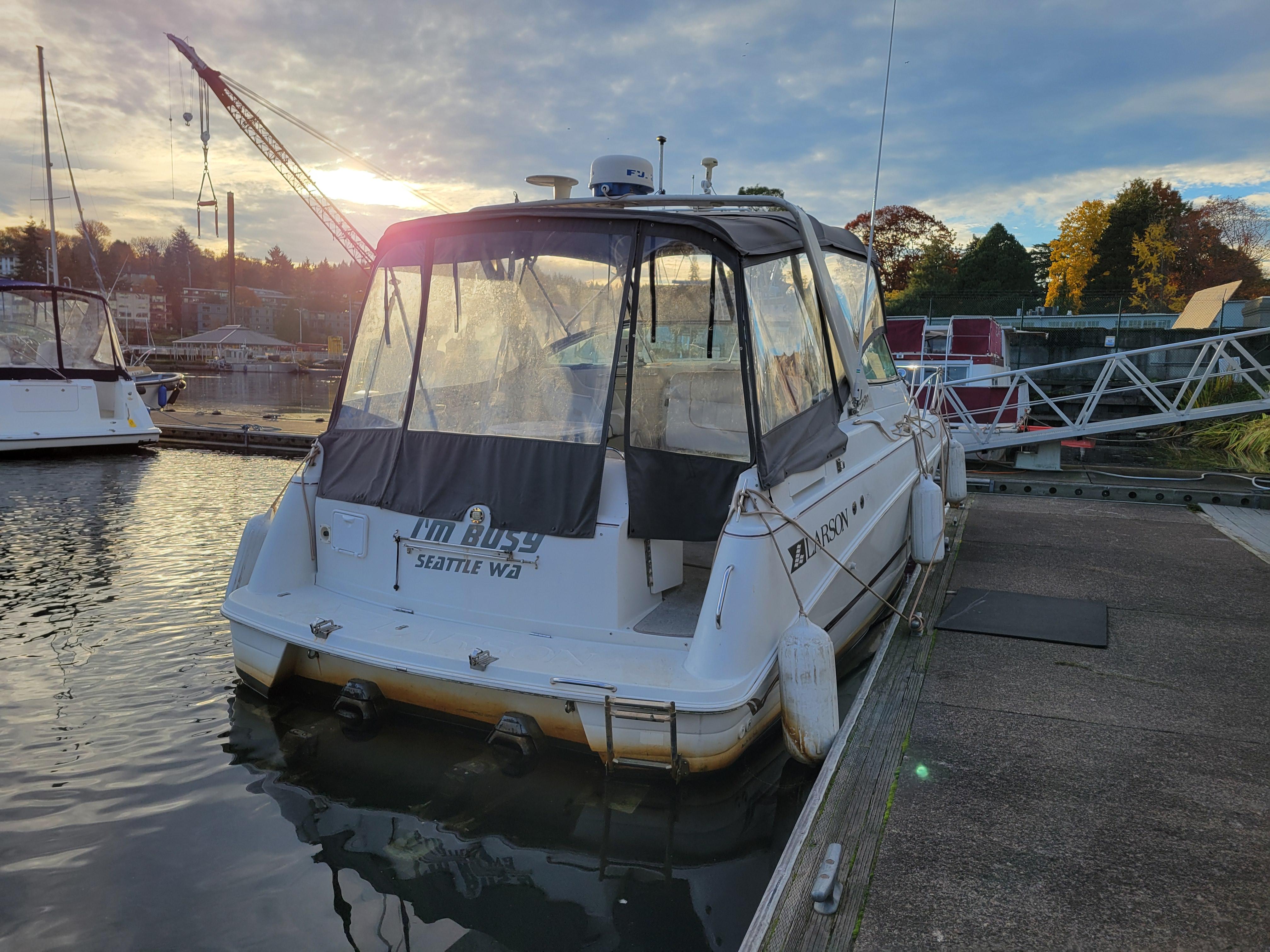 1997 Larson 290 Cabrio boat docked at marina during sunset.