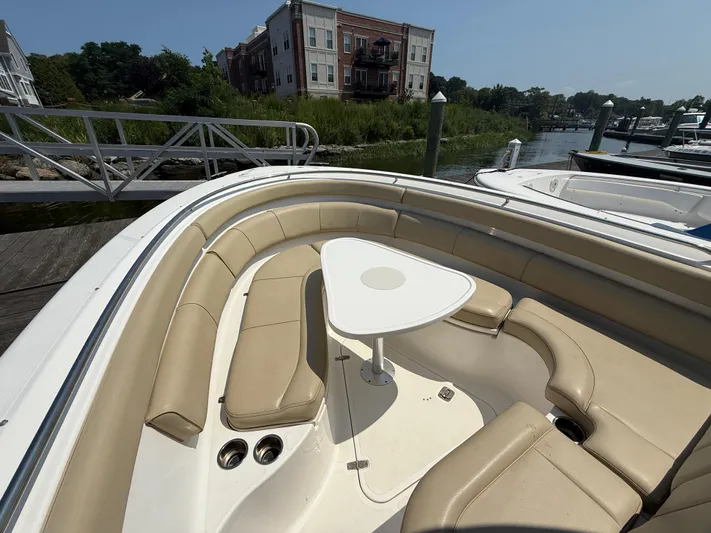 Savages Yacht Photos Pics 2015 Pursuit ST 310 Sport boat with beige seating and table, docked near waterfront homes.