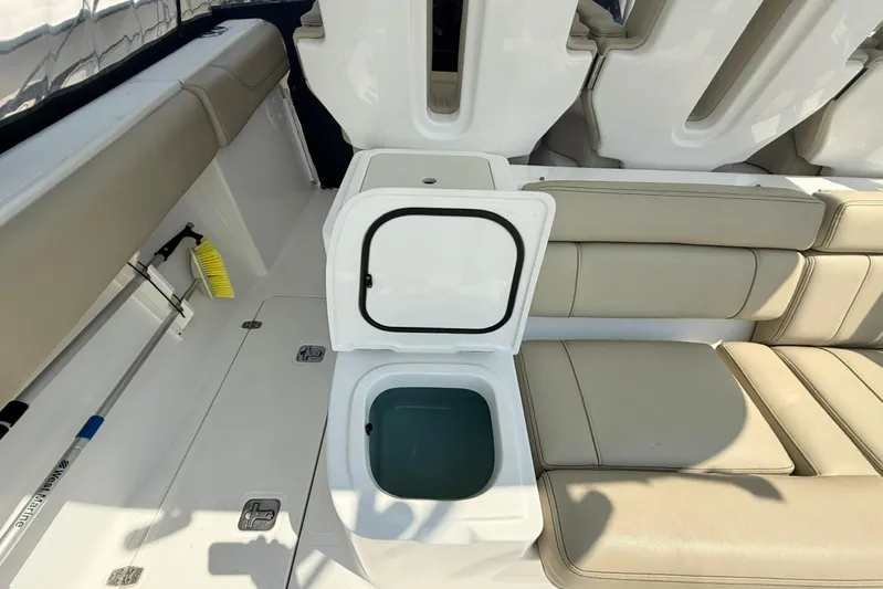 Savages Yacht Photos Pics 2015 Pursuit ST 310 Sport boat interior with open storage compartment and beige seating.