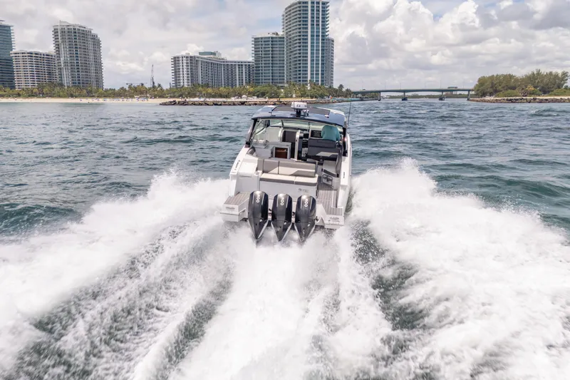  Yacht Photos Pics 2021 Cruisers Yachts 38 GLS speeding on water near city skyline.