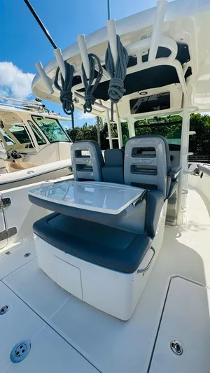  Yacht Photos Pics 2023 Boston Whaler 330 Outrage boat interior with seating and table under a clear blue sky.