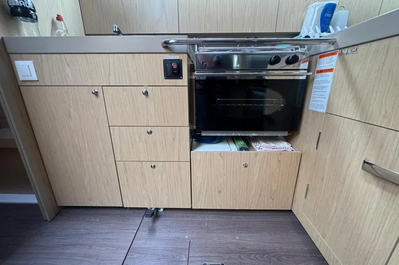 Bambino Yacht Photos Pics Modern kitchen area in a 2019 Beneteau Oceanis 41.1 yacht, featuring wood cabinetry.