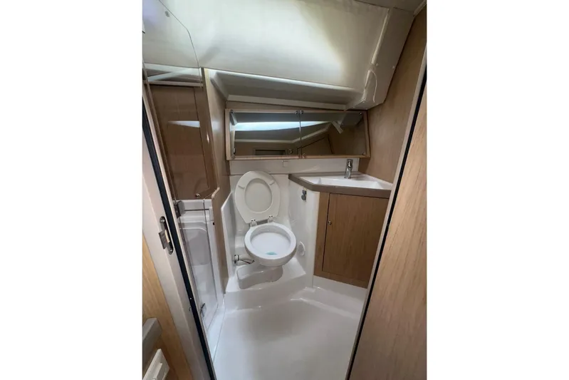 Bambino Yacht Photos Pics 2019 Beneteau Oceanis 41.1 yacht bathroom with toilet, sink, and wooden cabinetry.