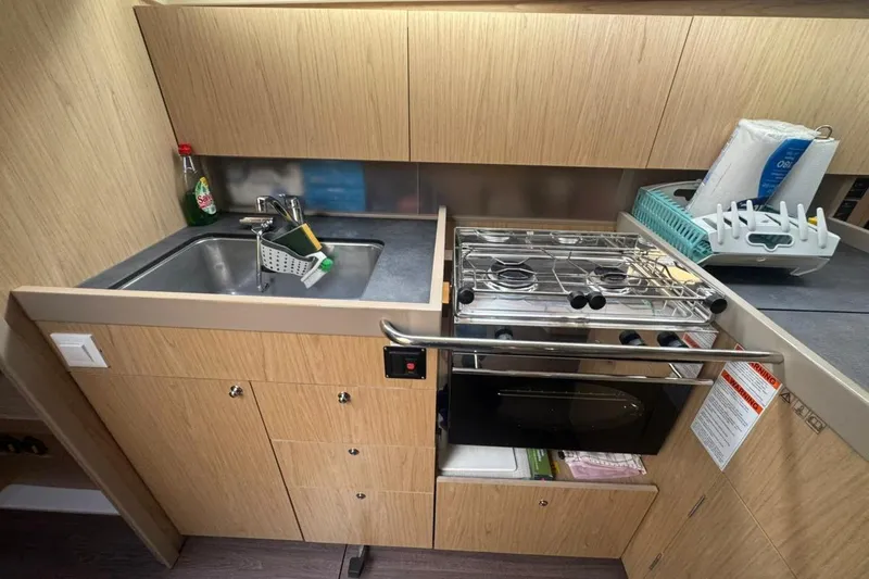 Bambino Yacht Photos Pics Compact kitchen in 2019 Beneteau Oceanis 41.1 yacht with sink, stove, and storage.