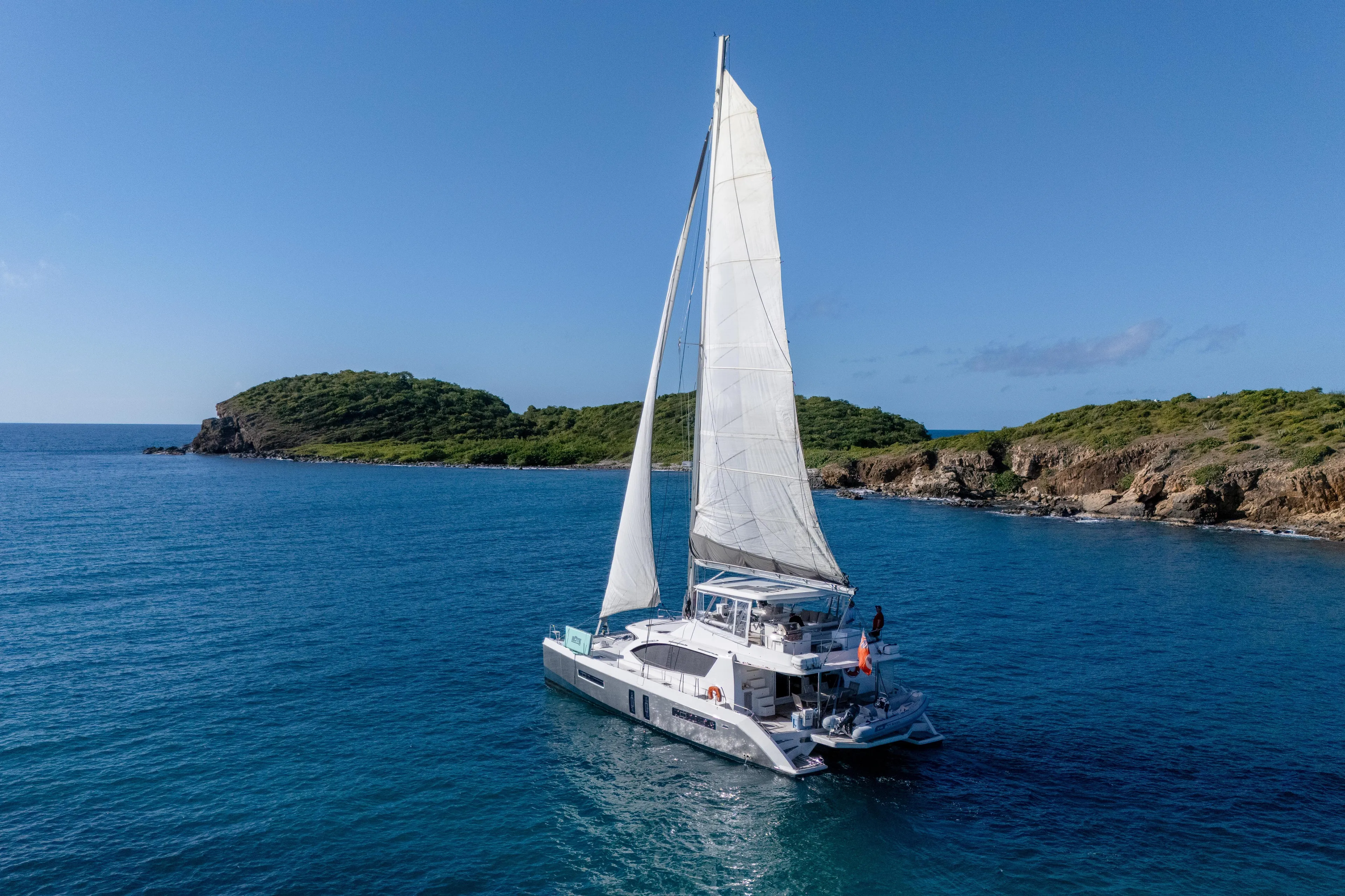 Sailing catamaran Leopard 58, 2014 model, cruising near lush green islands.