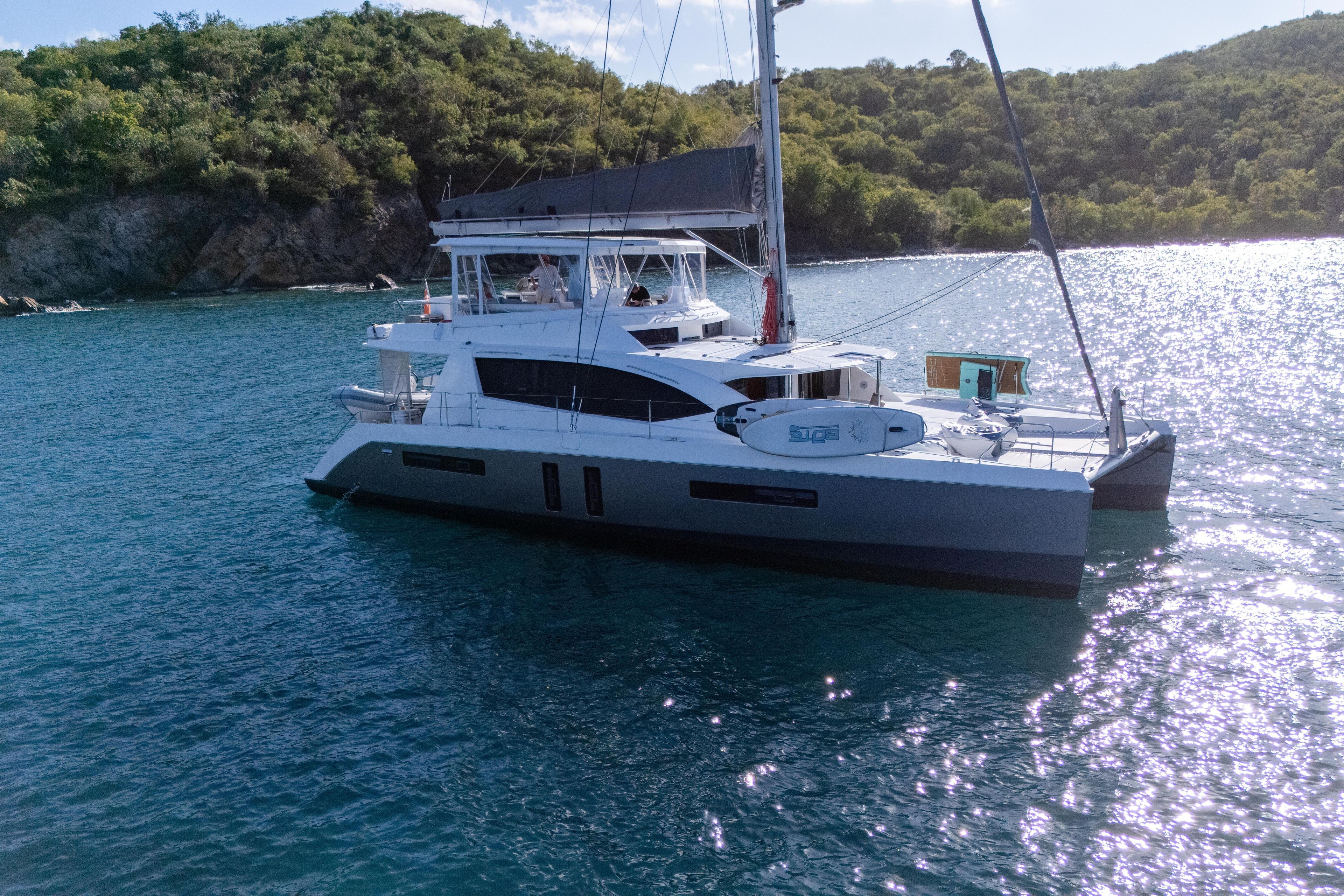 Luxury Leopard 58 catamaran sailing in serene waters, 2014 model, near lush green coastline.