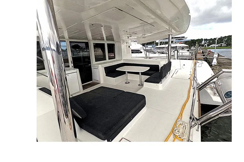 Rhapsody Yacht Photos Pics 2021 Lagoon 52 F yacht deck with seating and table, docked at marina.