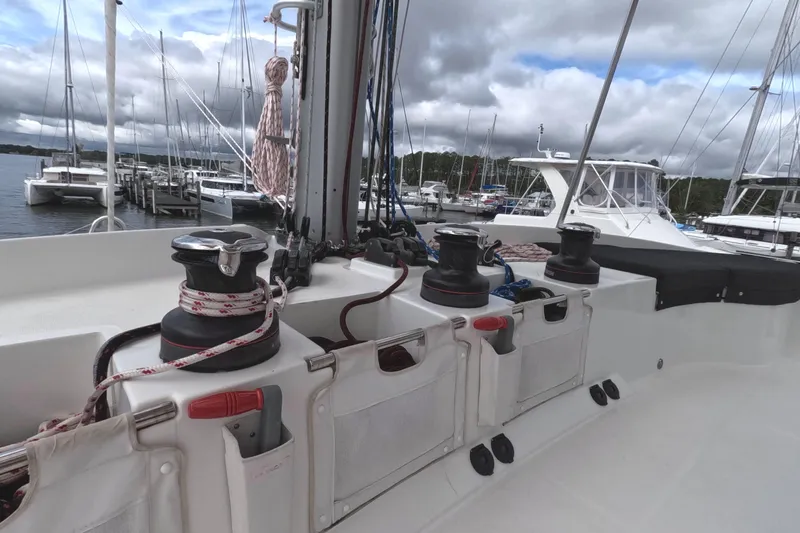 Rhapsody Yacht Photos Pics Lagoon 51 yacht deck with winches and ropes, docked at a marina under cloudy skies.