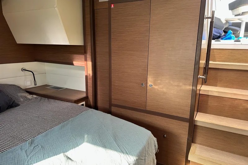 Rhapsody Yacht Photos Pics Luxurious interior cabin of 2021 Lagoon 52 F yacht with wooden finishes and cozy bedding.