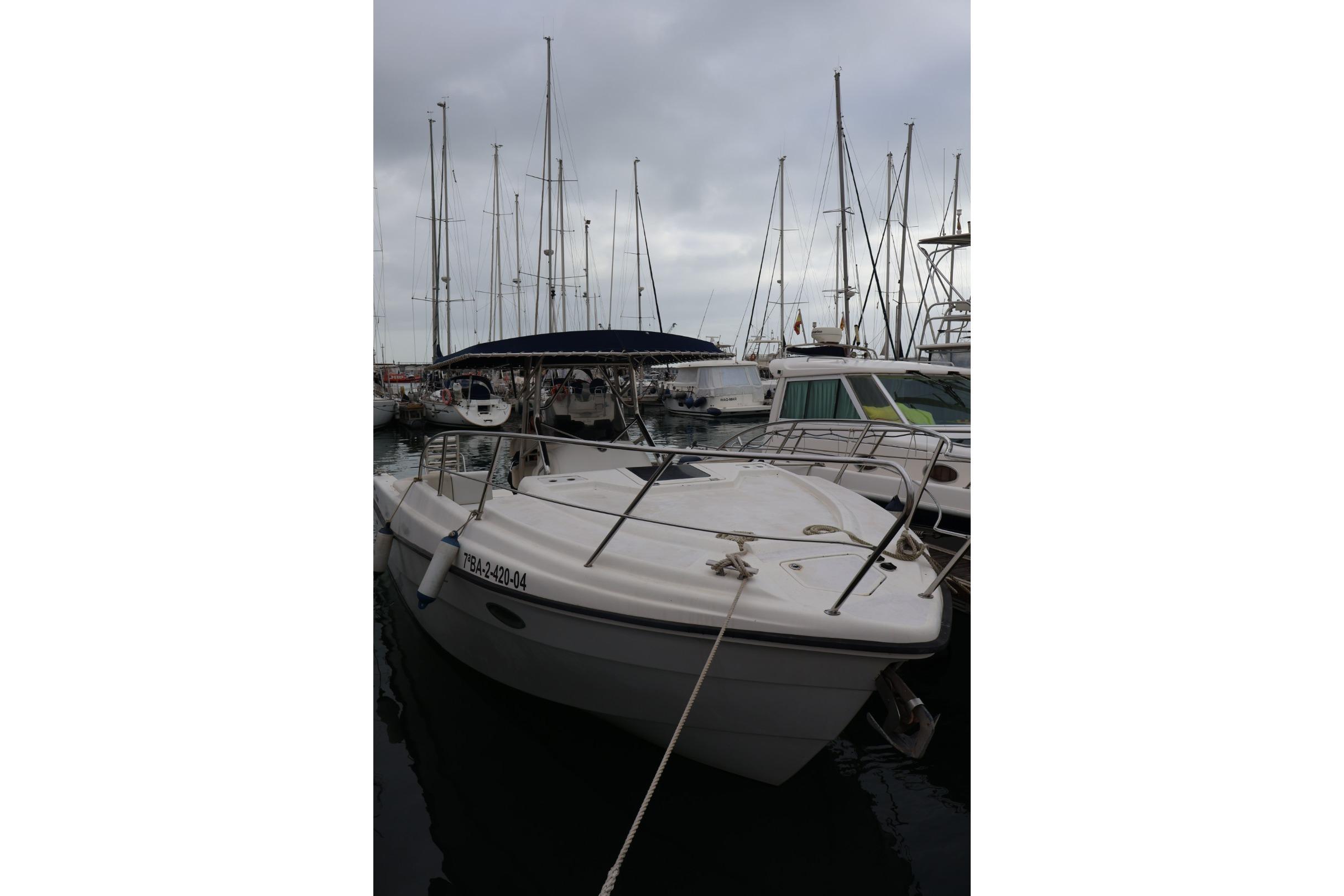 2004 Quer 32 Cuddy boat docked in a marina with overcast skies.