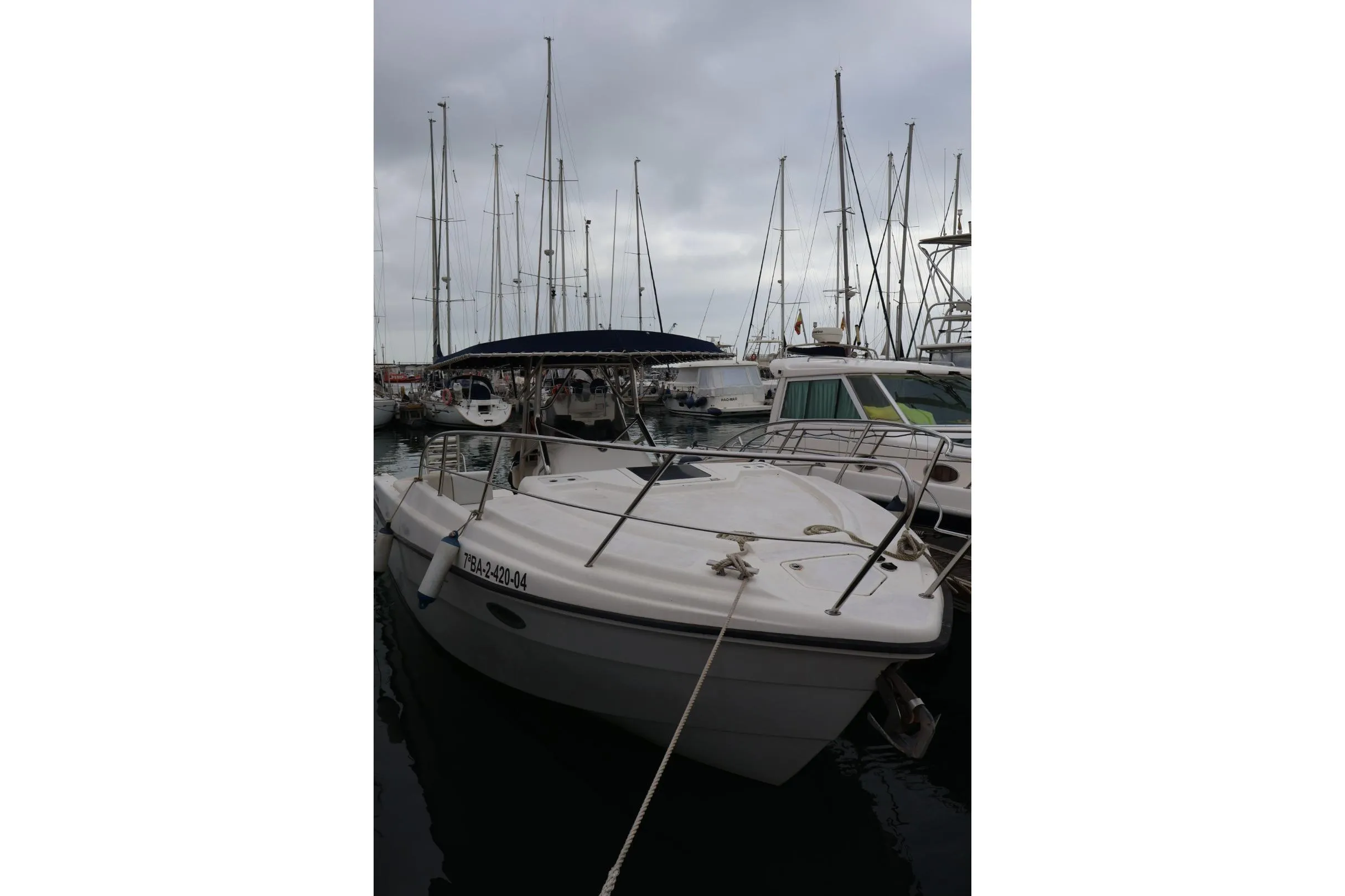 2004 Quer 32 Cuddy boat docked in a marina with overcast skies.