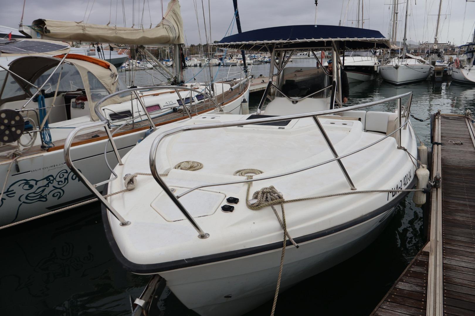 2004 Quer 32 Cuddy boat docked in a marina, surrounded by other sailboats.