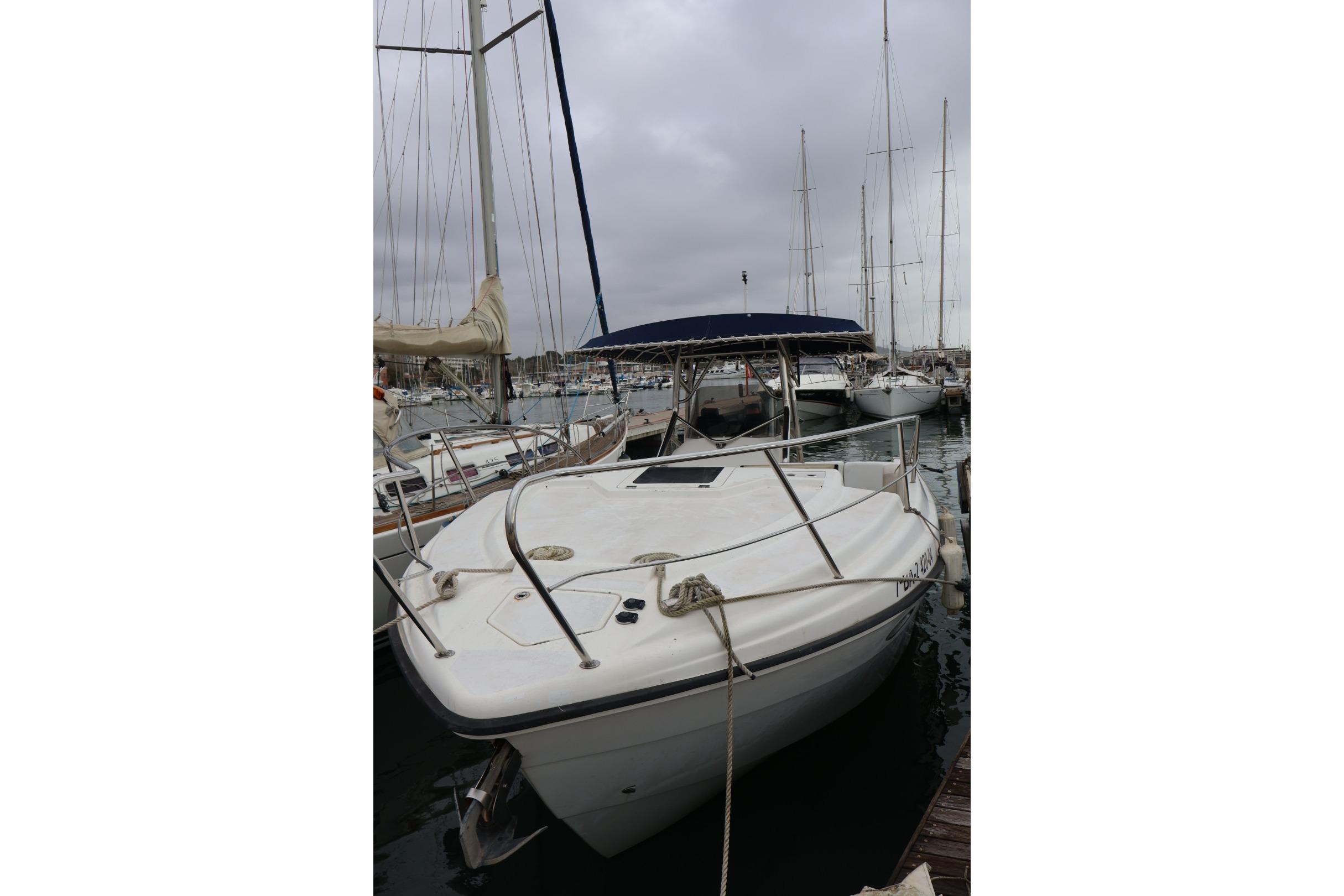 2004 Quer 32 Cuddy boat docked in a marina under cloudy skies.