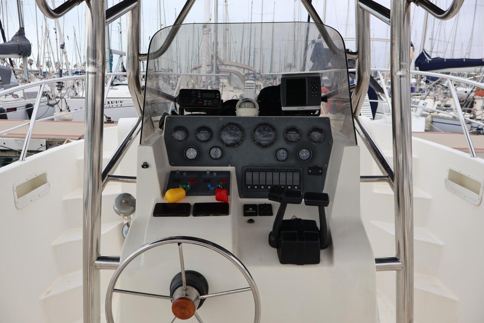 Cockpit of 2004 Quer 32 Cuddy boat with steering wheel and control panel.