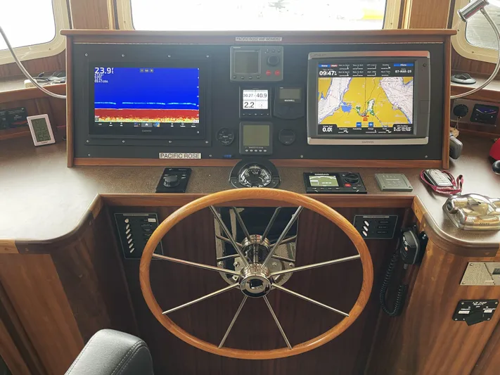 Pacific Rose Yacht Photos Pics Control panel of a 2009 American Tug 49 Limited with navigation screens and steering wheel.