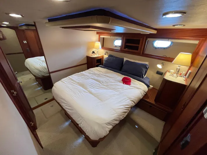 Pacific Rose Yacht Photos Pics Luxurious bedroom interior of 2009 American Tug 49 Limited yacht, featuring cozy bedding and elegant wood finishes.