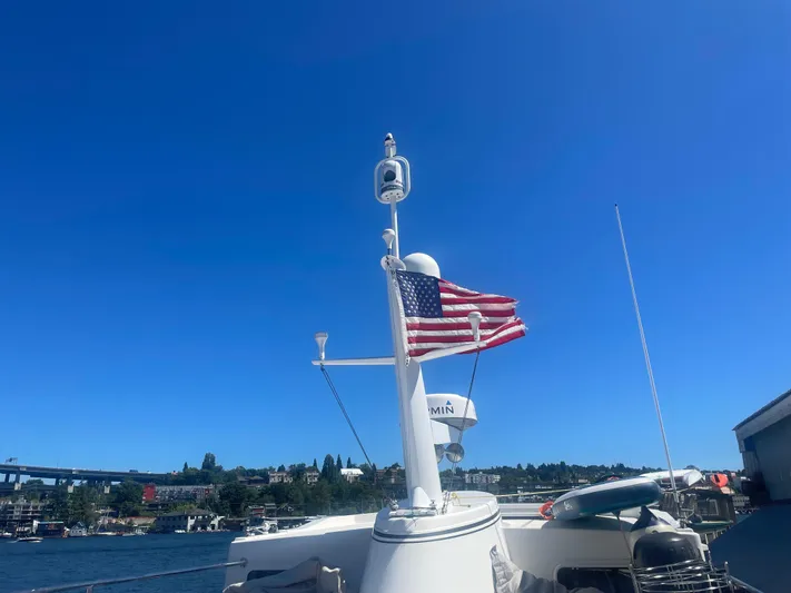 Pacific Rose Yacht Photos Pics American Tug 49 Limited 2009 with U.S. flag on a sunny day by the water.