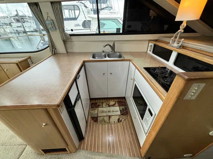Lady James Yacht Photos Pics Compact kitchen area in a 2000 Bayliner 3788 Command Bridge Motoryacht with sink, stove, and microwave.