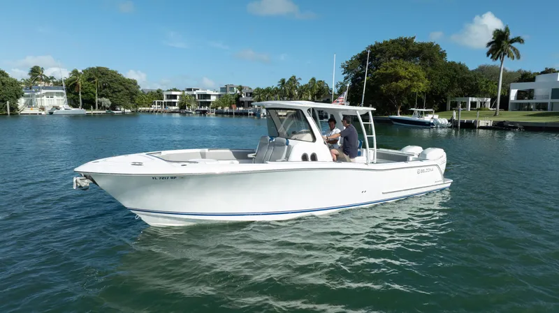  Yacht Photos Pics 2018 Belzona 325 Center Console boat on calm water, surrounded by lush greenery.