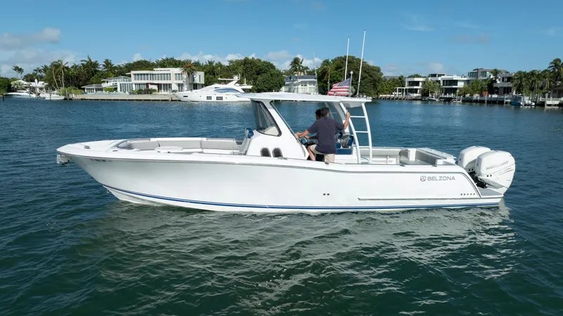  Yacht Photos Pics 2018 Belzona 325 Center Console boat on calm water, with modern waterfront homes in the background.